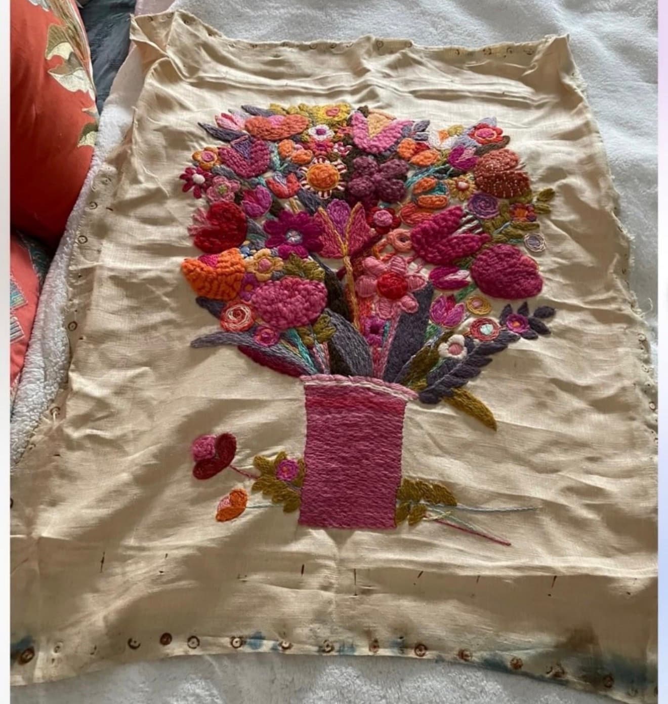 Vintage crewel embroidery floral bouquet as found — unframed on raw linen with visible staining and staple holes along the edges